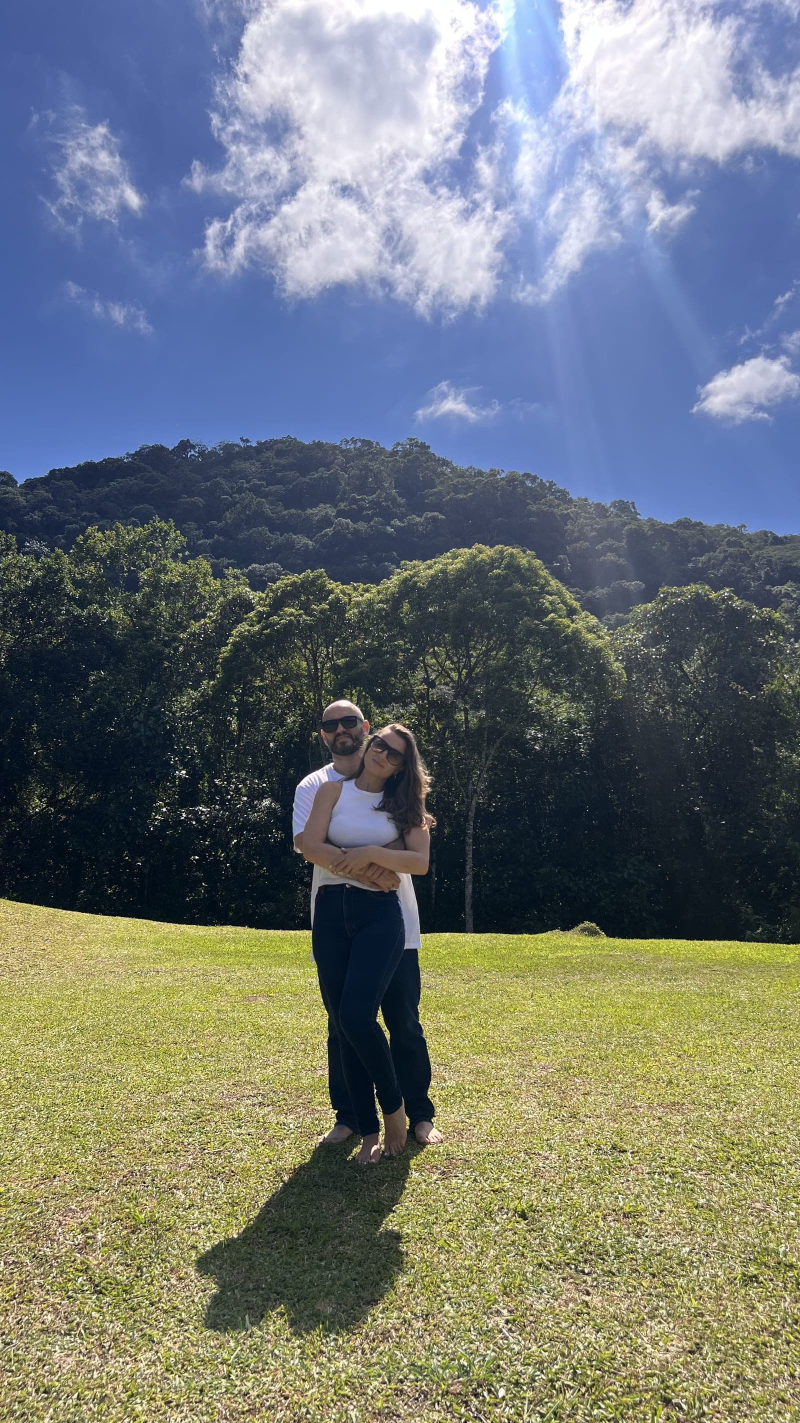 Bruno e Josélia abraçados no campo, com montanhas ao fundo