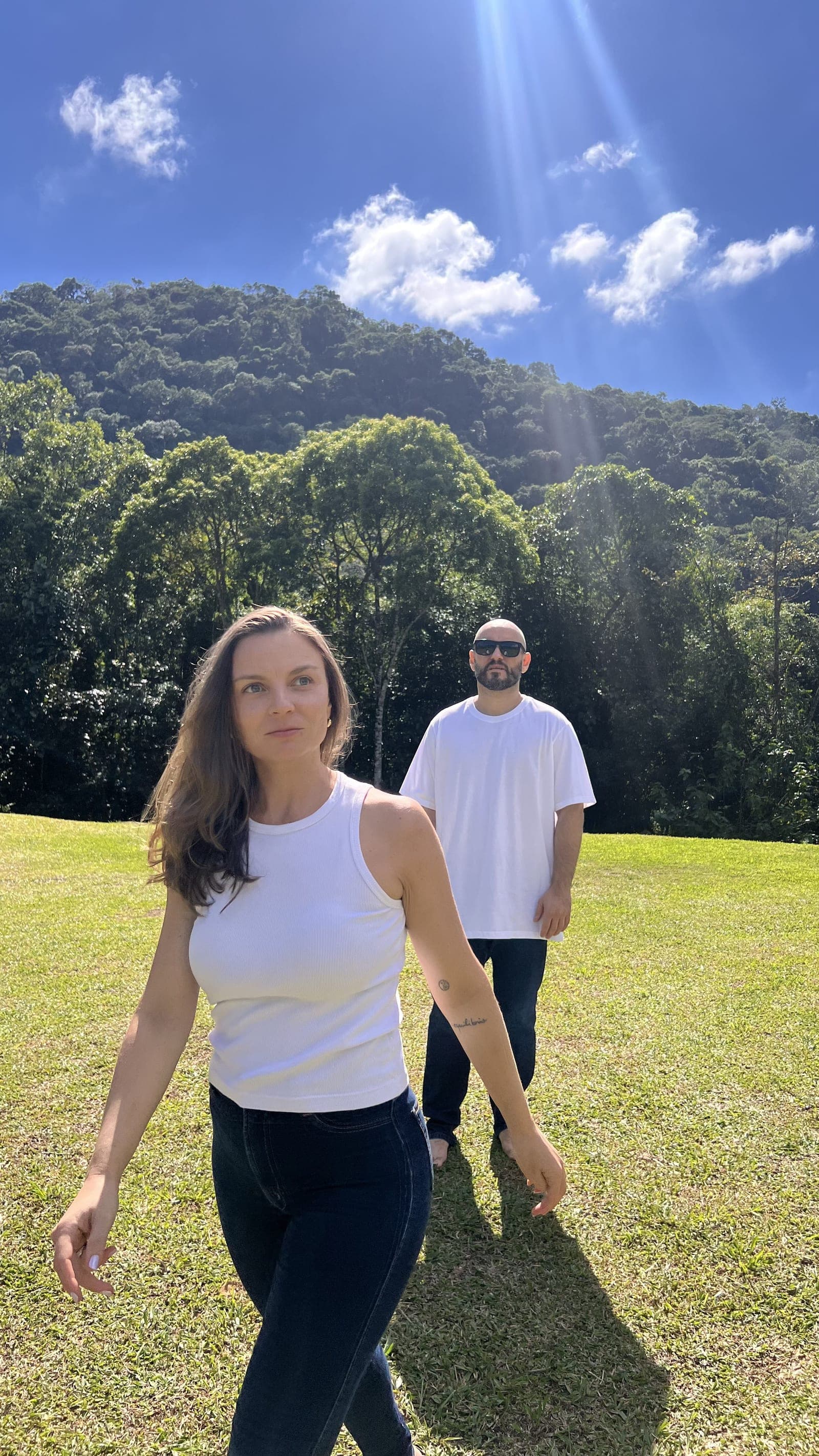 Bruno e Josélia caminhando no gramado com a mata ao fundo